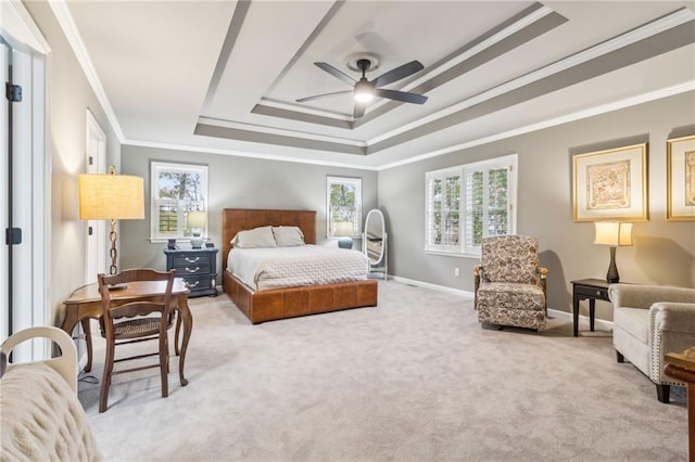 carpeted bedroom with multiple windows, ceiling fan, crown molding, and a tray ceiling