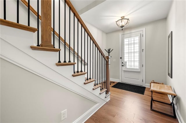 entryway with stairway, baseboards, and wood finished floors