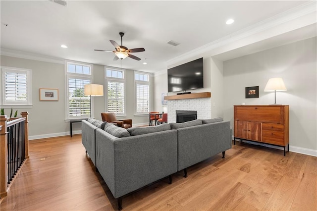 living room featuring visible vents, light wood-style flooring, a brick fireplace, and ornamental molding