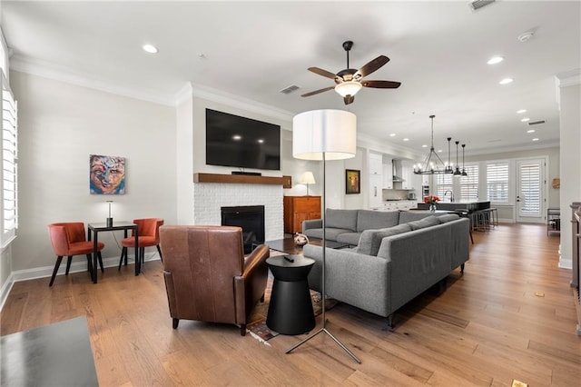 living area featuring light wood-type flooring, recessed lighting, crown molding, baseboards, and a brick fireplace