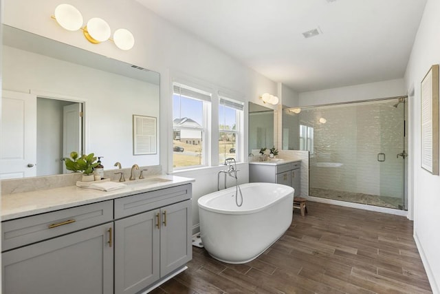 828 Chestnut Pl, Milton, GA 30004 - bathroom featuring a stall shower, two vanities, wood finished floors, and a freestanding tub