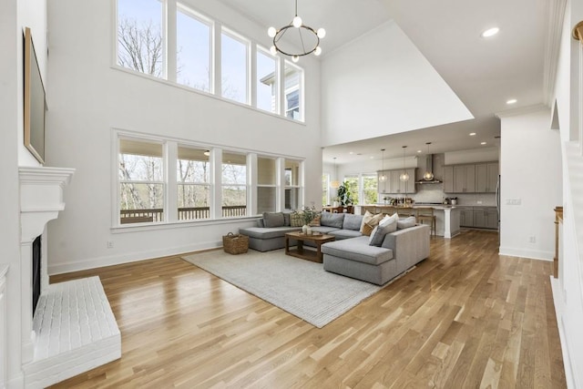 828 Chestnut Pl, Milton, GA 30004 - living area featuring a fireplace with raised hearth, a chandelier, light wood finished floors, baseboards, and a towering ceiling