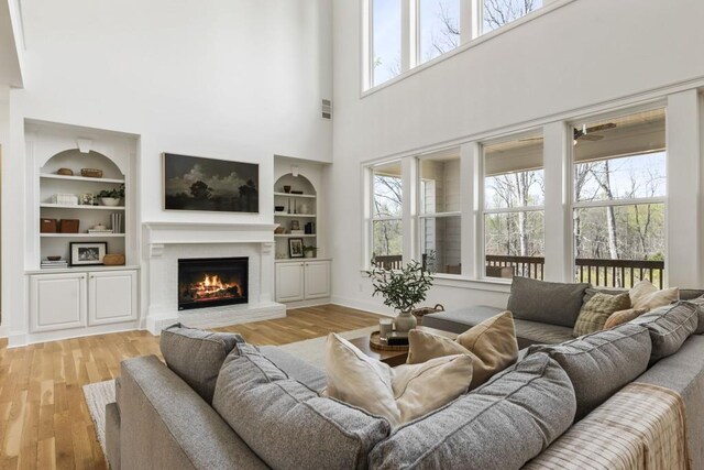 828 Chestnut Pl, Milton, GA 30004 - living area with built in shelves, a lit fireplace, wood finished floors, a high ceiling, and baseboards