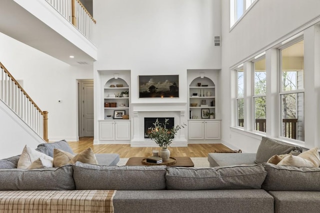 828 Chestnut Pl, Milton, GA 30004 - living room with light wood finished floors, a high ceiling, baseboards, stairs, and built in shelves