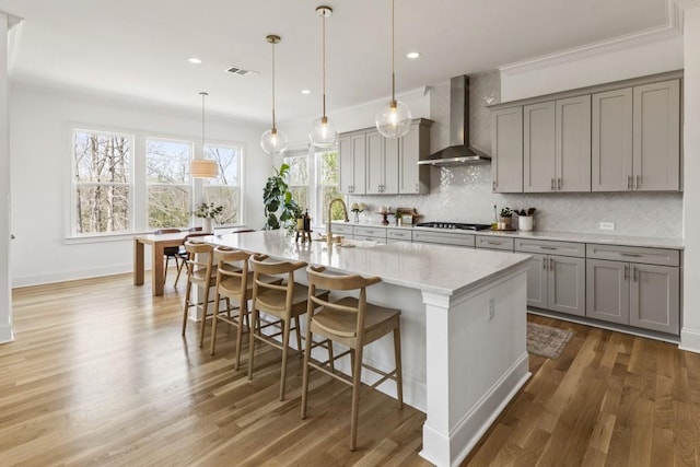 828 Chestnut Pl, Milton, GA 30004 - kitchen featuring wall chimney exhaust hood, gray cabinets, gas cooktop, tasteful backsplash, and a kitchen bar