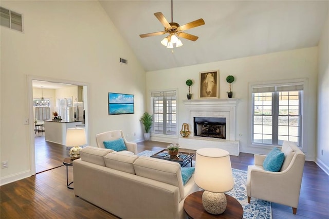 living room featuring visible vents, a fireplace with raised hearth, dark wood finished floors, and a ceiling fan