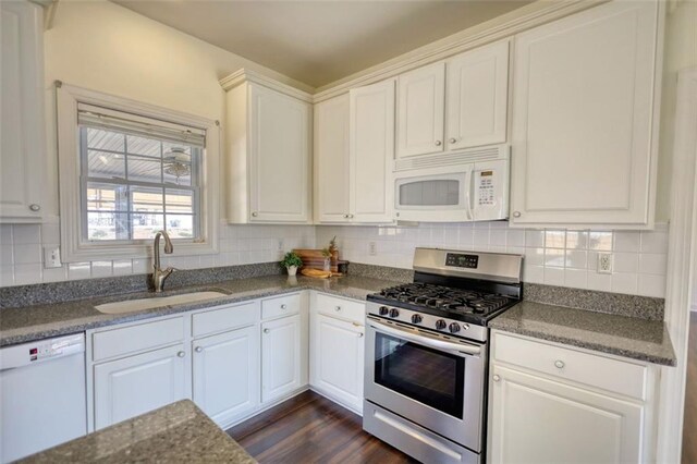 kitchen with a sink, backsplash, white cabinets, white appliances, and dark wood-style flooring
