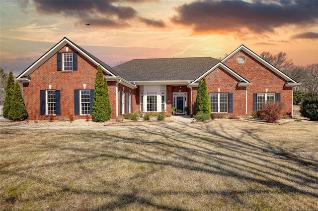 view of front of house with brick siding and a lawn