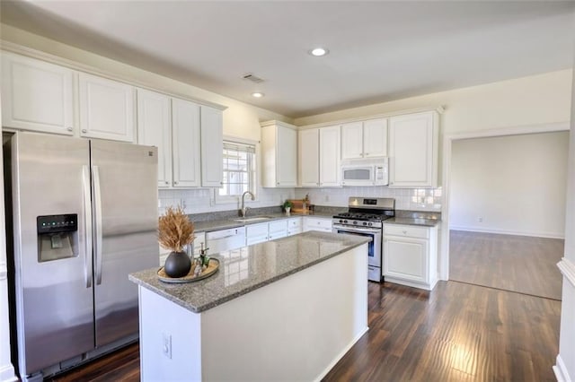 kitchen with visible vents, backsplash, appliances with stainless steel finishes, white cabinetry, and a sink