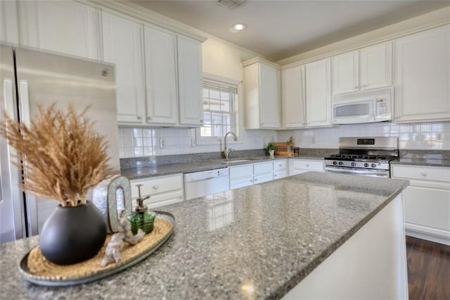 kitchen featuring white appliances, tasteful backsplash, and white cabinetry