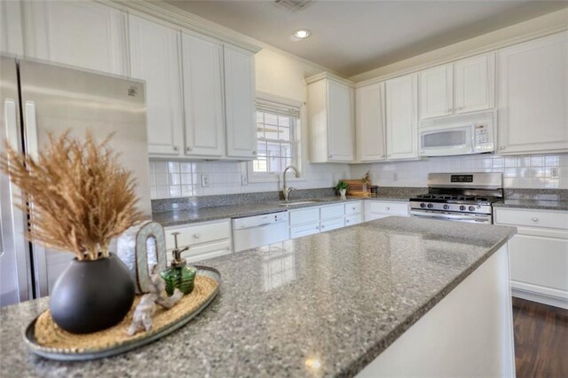 kitchen with decorative backsplash, white appliances, and white cabinetry