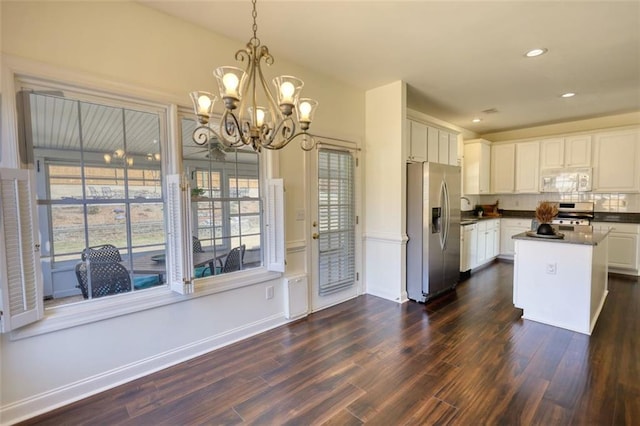 kitchen featuring dark countertops, a chandelier, appliances with stainless steel finishes, white cabinets, and dark wood-style flooring