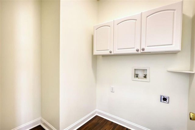 clothes washing area featuring electric dryer hookup, dark wood-type flooring, washer hookup, cabinet space, and baseboards