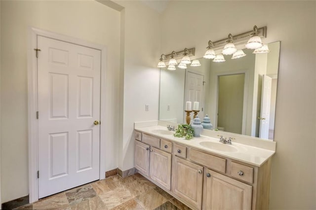 bathroom featuring a sink, baseboards, toilet, and double vanity