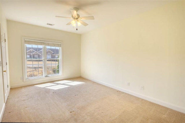 empty room featuring visible vents, light carpet, baseboards, and ceiling fan