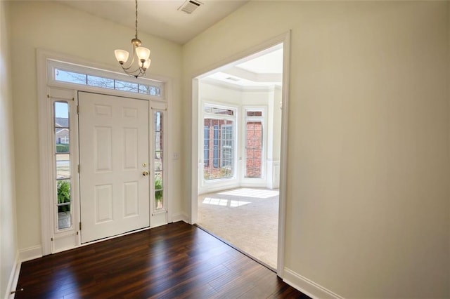 entrance foyer with visible vents, baseboards, dark wood-type flooring, and an inviting chandelier