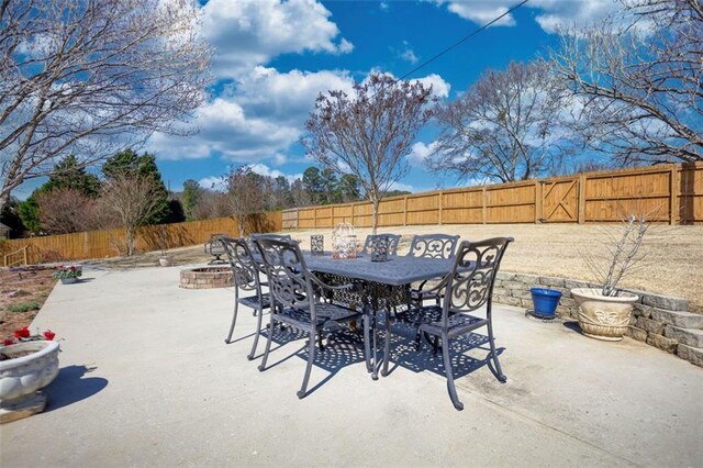 view of patio with an outdoor fire pit, outdoor dining area, and a fenced backyard