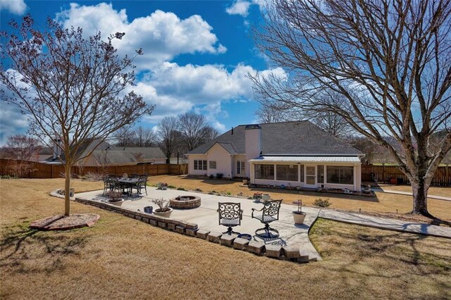 rear view of property with a patio area, a lawn, a fenced backyard, and a fire pit