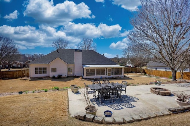 rear view of house featuring a patio area, a fenced backyard, a fire pit, and a yard