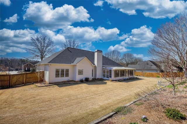 rear view of house featuring a lawn, fence, a sunroom, and a chimney