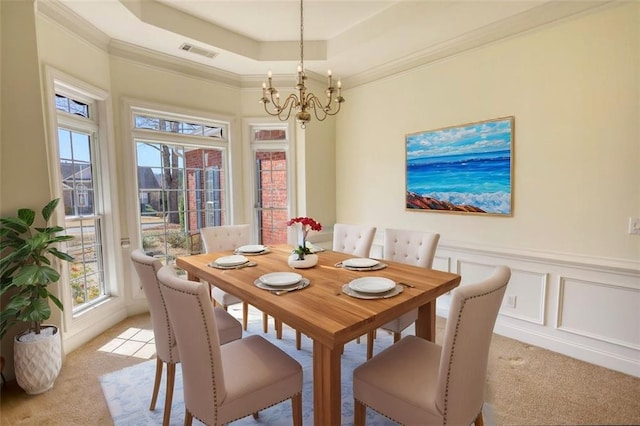 dining area with visible vents, light carpet, a tray ceiling, an inviting chandelier, and a decorative wall