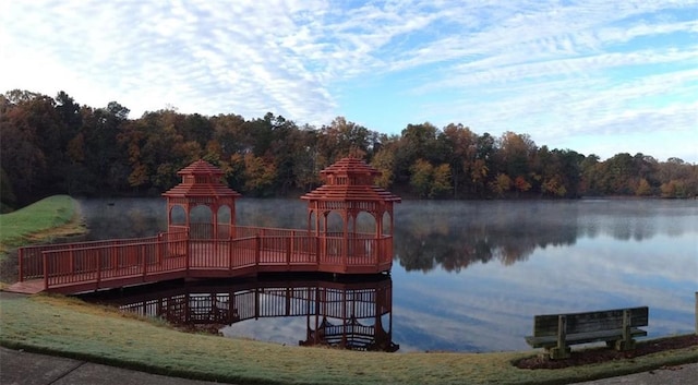 view of dock featuring a gazebo, a water view, and a view of trees