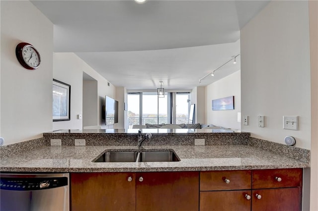 kitchen with kitchen peninsula, rail lighting, light stone counters, sink, and dishwasher