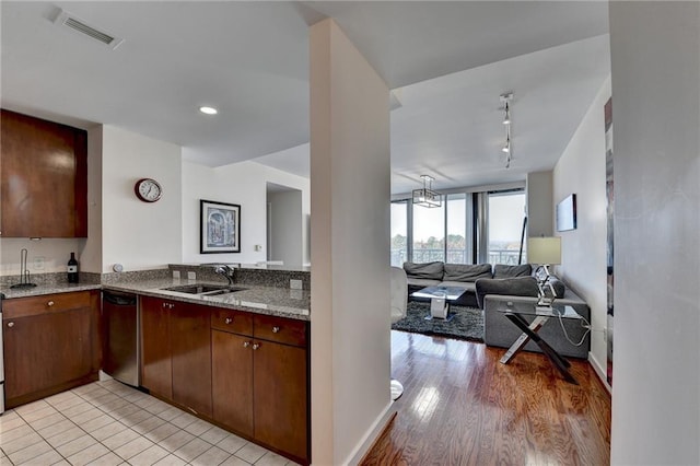 kitchen featuring rail lighting, light stone counters, stainless steel dishwasher, sink, and light hardwood / wood-style floors