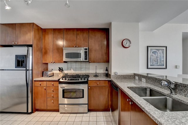 kitchen with light stone counters, sink, light tile patterned floors, and stainless steel appliances