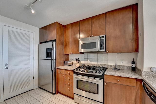 kitchen with light stone countertops, light tile patterned floors, and appliances with stainless steel finishes