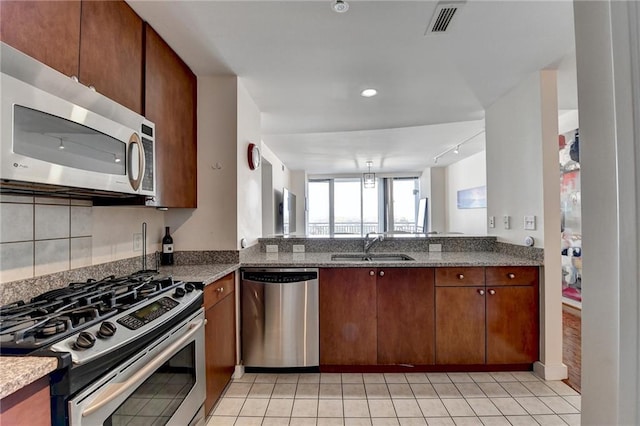 kitchen with stone counters, light tile patterned floors, stainless steel appliances, and sink