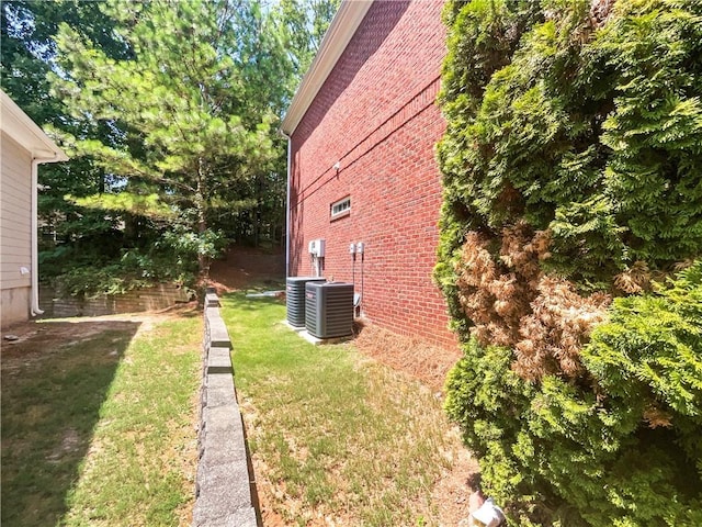 view of side of home featuring cooling unit and a yard