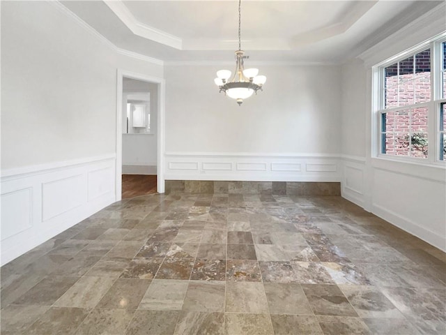 empty room featuring ornamental molding, a raised ceiling, and a notable chandelier