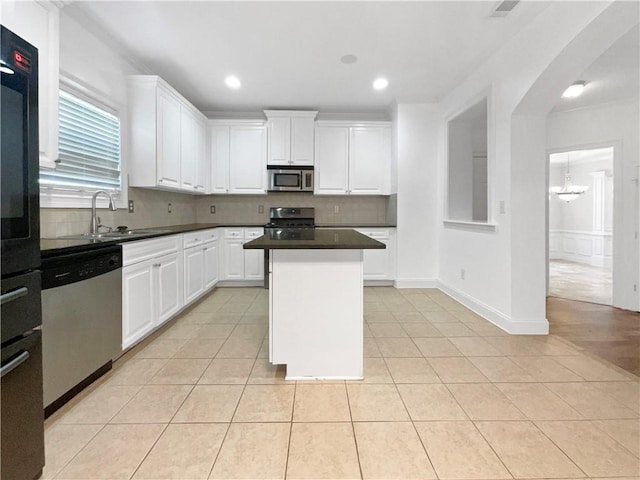 kitchen with a kitchen island, light tile patterned flooring, sink, white cabinetry, and stainless steel appliances