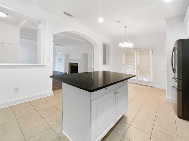 kitchen featuring light tile patterned floors, white cabinets, stainless steel fridge, and hanging light fixtures