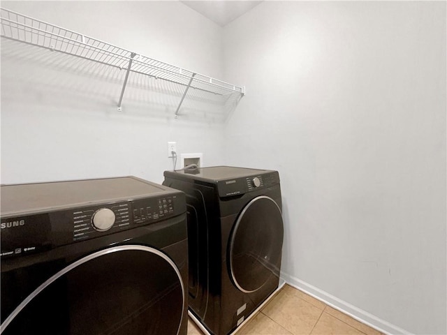 clothes washing area with light tile patterned floors and washer and dryer