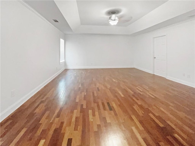 spare room with wood-type flooring and a tray ceiling