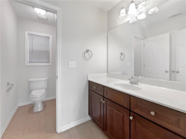 bathroom with toilet, vanity, and tile patterned flooring