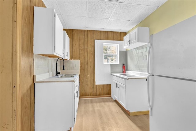 kitchen featuring tasteful backsplash, light wood-type flooring, light countertops, freestanding refrigerator, and a sink