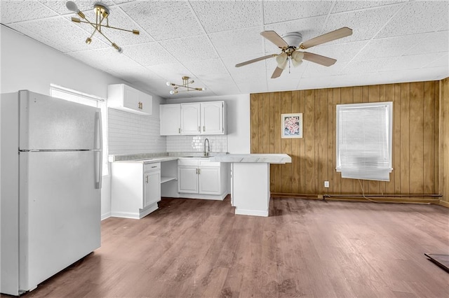 kitchen featuring ceiling fan, light countertops, freestanding refrigerator, wood finished floors, and white cabinetry