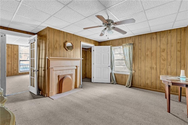 interior space featuring carpet, a ceiling fan, and wood walls