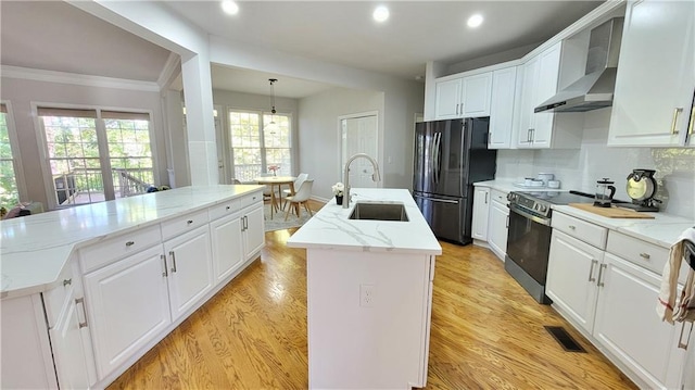 kitchen featuring sink, black refrigerator, an island with sink, stainless steel electric stove, and wall chimney range hood