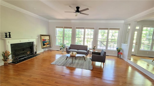 living room featuring a wealth of natural light, ornamental molding, and light wood-type flooring