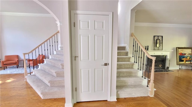 staircase featuring wood-type flooring, ornamental molding, and ornate columns