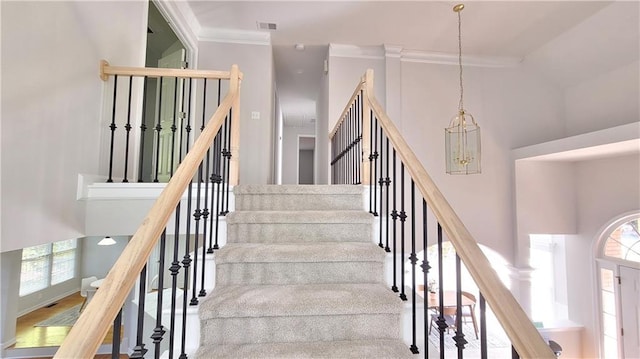 stairs featuring crown molding and a high ceiling