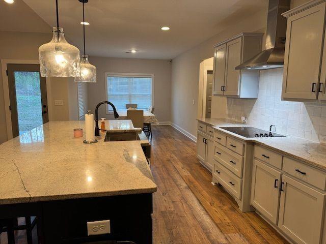 224 Crest Creek Way, Villa Rica, GA 30180 - kitchen with wall chimney exhaust hood, black electric cooktop, tasteful backsplash, a large island with sink, and healthy amount of natural light