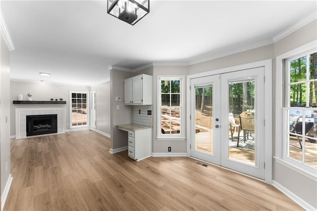 4816 Morning Chase NW, Acworth, GA 30102 - kitchen featuring french doors, light wood-type flooring, crown molding, a tile fireplace, and white cabinetry