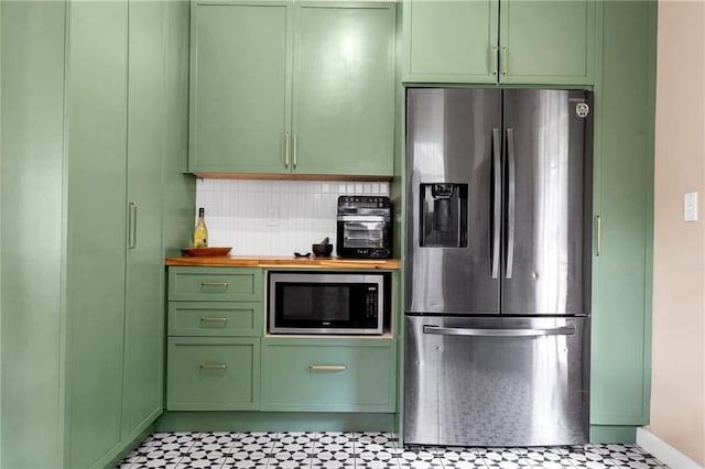 kitchen featuring stainless steel appliances, green cabinets, wood counters, tasteful backsplash, and baseboards