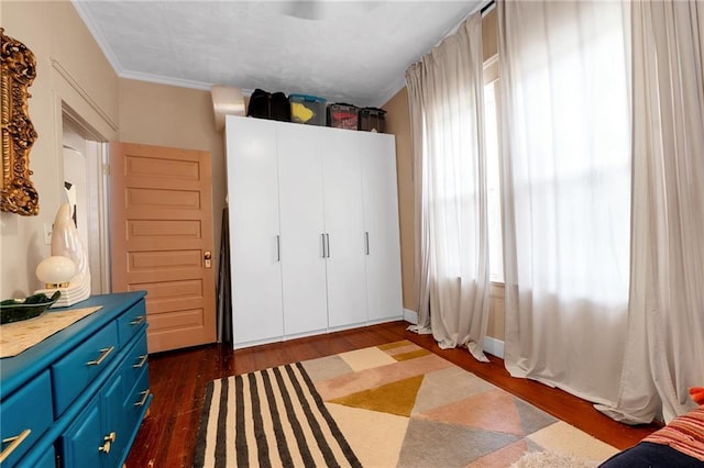 bedroom featuring dark wood-style flooring, ornamental molding, and multiple windows