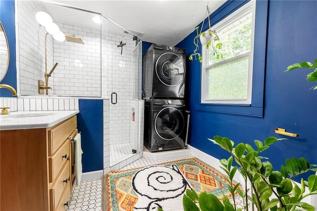 washroom with estacked washer and dryer, a sink, and baseboards